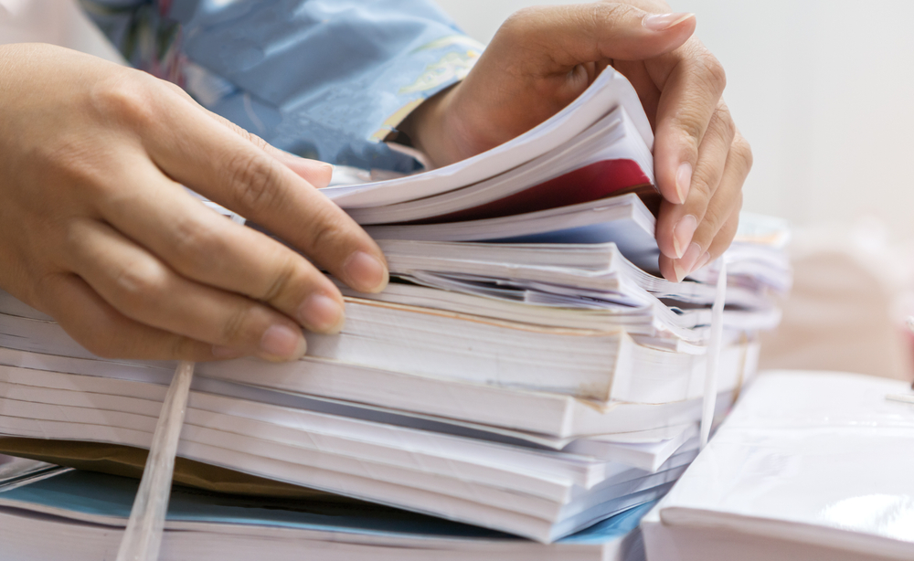Businesswoman,Working,In,Stacks,Of,Paperwork,Files,For,Searching,Infomation